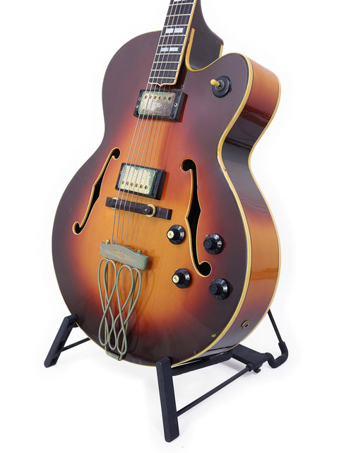 A Yamaha AE1200 guitar, crafted in Japan in 1982, featuring a gorgeous sunburst finish, displayed on a stand.