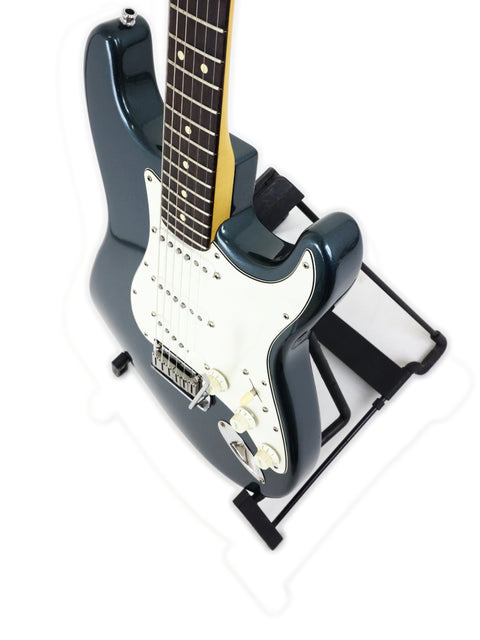 A black-bodied Fender Strat Plus Deluxe guitar from 1989 elegantly positioned on a stand, highlighting its classic appeal.
