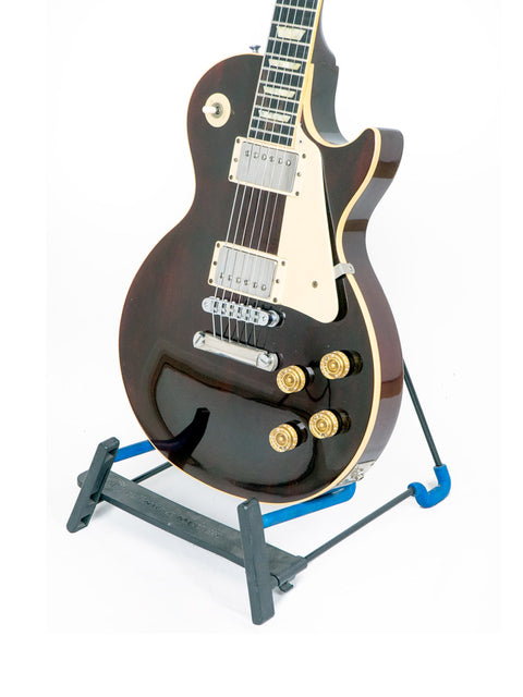 A black-bodied Gibson Les Paul Standard guitar from 1991 is positioned on a stand, emphasizing its timeless craftsmanship.