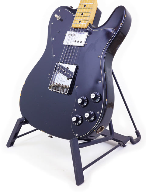 A black 1978 Fender Telecaster Custom guitar showcased on a stand, set against a stark white background.
