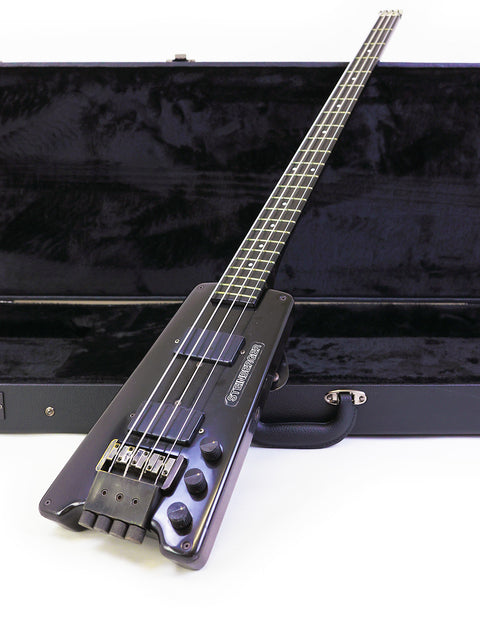 A black 1982 Steinberger L2 bass guitar in a case, highlighting its unique shape and vintage appeal.
