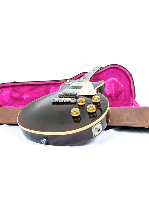 A black Gibson Les Paul Standard guitar, model year 1991, housed in its case on a plain white backdrop.