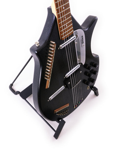 A black Jerry Jones Master Electric Sitar guitar resting on a stand, highlighted by a stark white background.