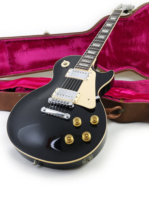 A black electric guitar, a 1995 Gibson Les Paul Standard, nestled in its case, showcasing its sleek design.