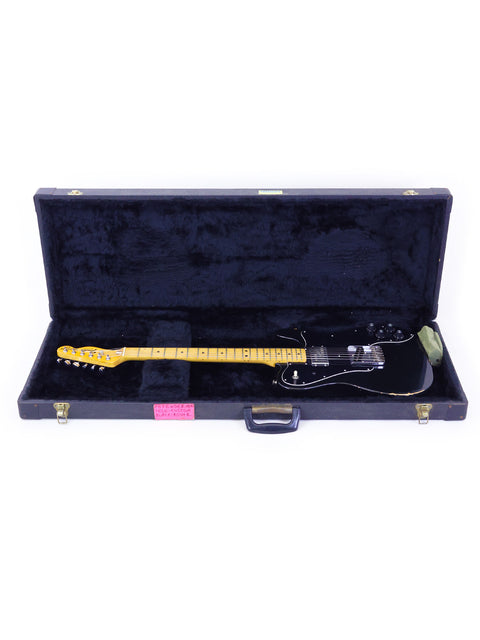 A black electric guitar, specifically a 1978 Fender Telecaster Custom, displayed in its case on a white background.
