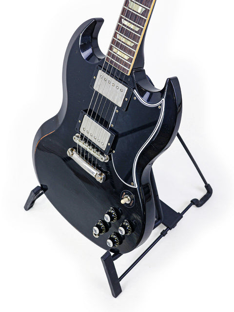 A black electric guitar, the Gibson Custom Shop '64 SG Murphy Lab, elegantly displayed on a stand.