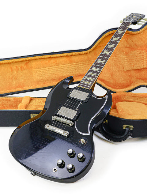 A black electric guitar with its case, highlighting the Gibson Custom Shop '64 SG Murphy Lab from the USA, 2022.
