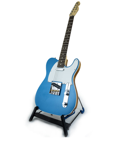 A blue electric guitar on a stand, highlighting the Txxx Custom Style Partscaster in Pelham Blue, made in the USA, 2020/2021.
