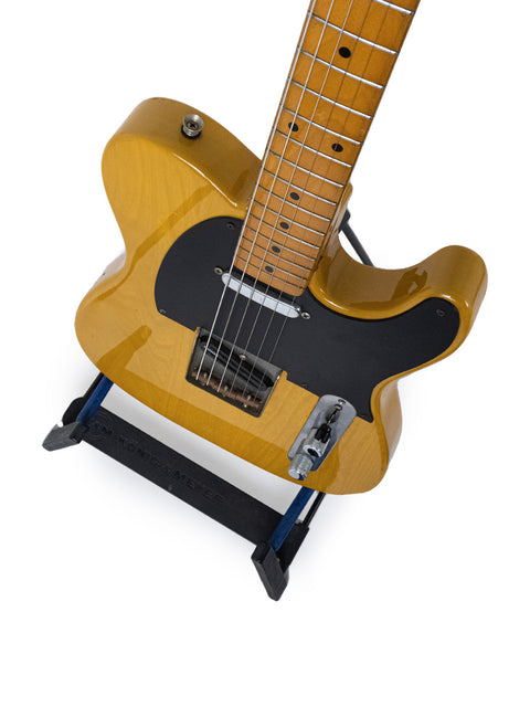 A bright yellow electric guitar, the Fender Squier JV Telecaster from 1984, elegantly displayed on a stand.