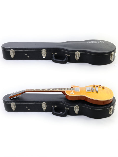 A case holds two guitars, prominently displaying a yellow Gibson Les Paul Standard from 2013, highlighting its beauty.