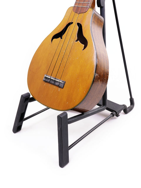 A classic 1927 Harmony Roy Smeck Vita-uke ukulele resting on a stand, ideal for enthusiasts seeking unique musical instruments.