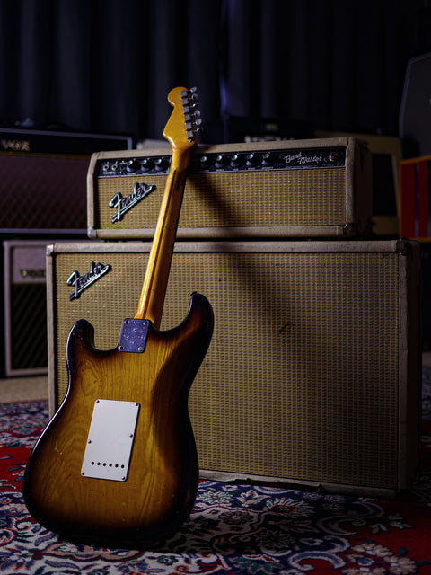 A classic 1954 Fender Stratocaster guitar alongside an amplifier, placed on a stylish rug.