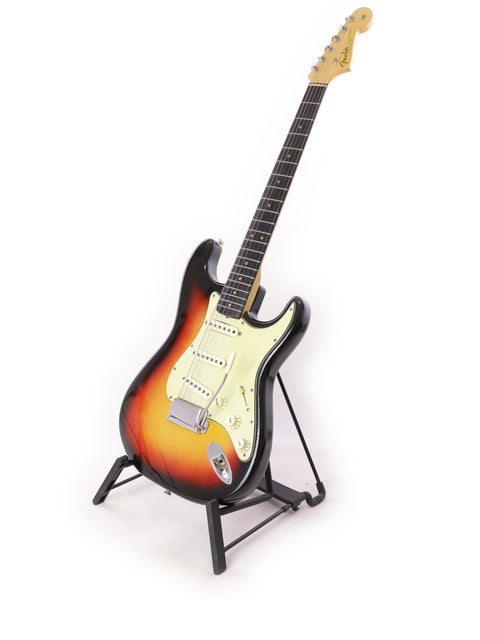 A classic 1964 Fender L Series Stratocaster in Fiesta Red resting on a stand, set against a clean white background.