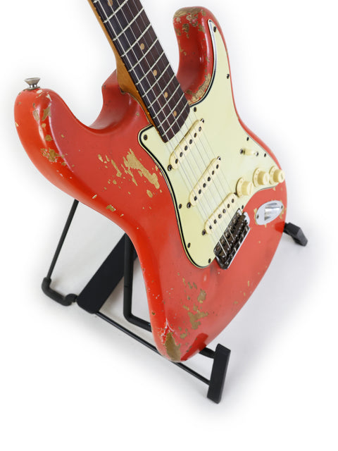 A classic 1964 Fender L Series Stratocaster in vibrant Fiesta Red, featuring a white pick guard, resting on a stand.