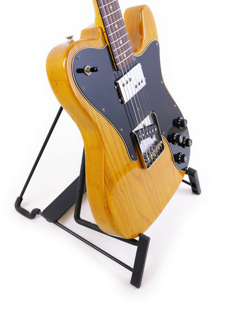 A classic Fender Telecaster Custom from 1977 showcased on a stand with a minimalist white background.