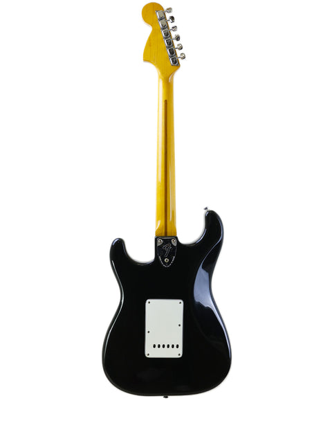 A classic black and yellow electric guitar, the 1981 Fender Stratocaster, stands out against a pristine white background.
