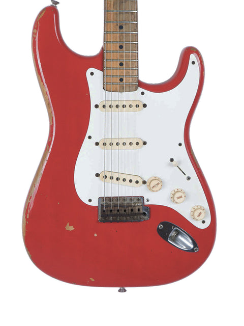 A classic red electric guitar, the 1958 Fender Stratocaster, adorned with a stylish white pickguard, ready to rock.
