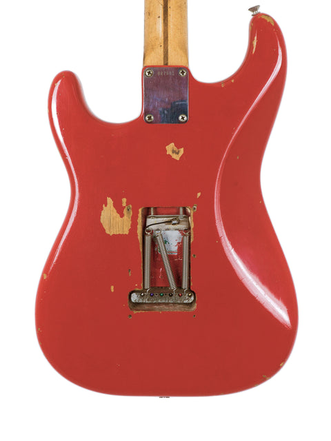 A classic red guitar, the 1958 Fender Stratocaster, with a wooden body and bridge, perfect for any music lover.