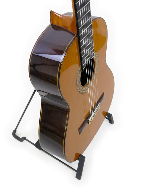 A classical guitar, Francisco Esteve 9C/B from Spain 2021, is displayed on a stand with a simple white backdrop.