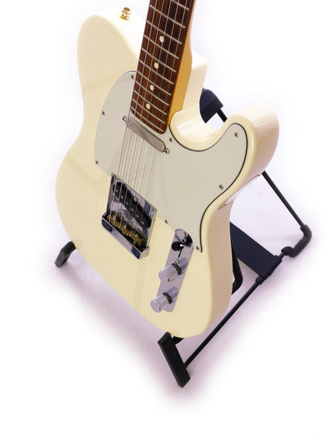 A cream-colored electric guitar on a black stand against a white background.