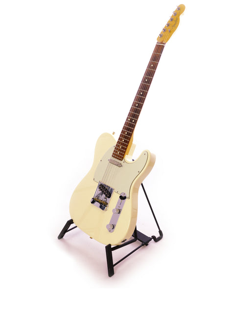 A cream-colored electric guitar on a black stand against a white background.