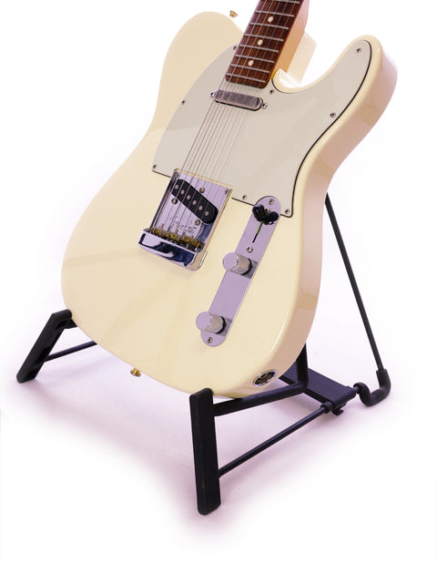 A cream-colored electric guitar resting on a black stand against a white background.