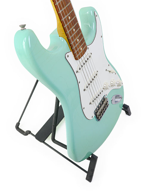 green electric guitar, specifically a 2003 Fender Custom Shop 1960's Closet Classic Stratocaster, positioned on a stand.