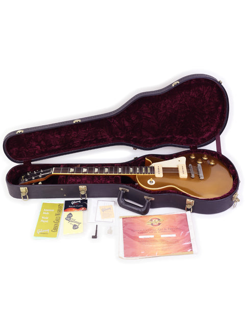 A guitar case opened to reveal a Gibson Custom Shop Historic Les Paul 1956 Reissue, showcasing its elegant design and upgrades.
