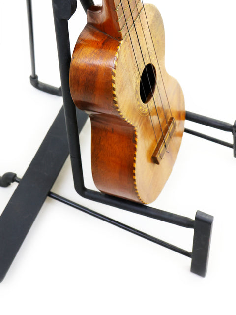 A historic 1917 Manuel Nunes Style #3 ukulele on a stand, highlighting its craftsmanship.