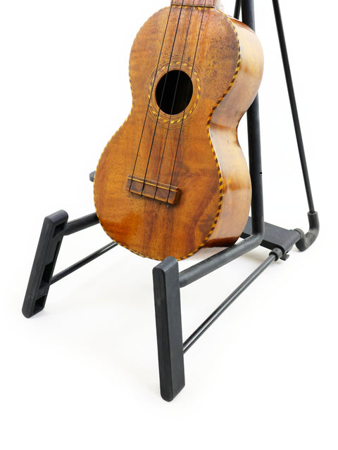  A historic 1917 Manuel Nunes Style #3 ukulele perched on a stand, ready for play.