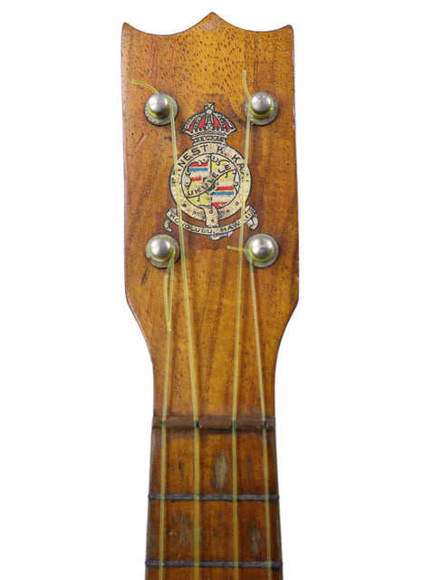  A historic 1918 Kaai Style 2 Koa Ukulele showcasing a unique crest design on the neck.