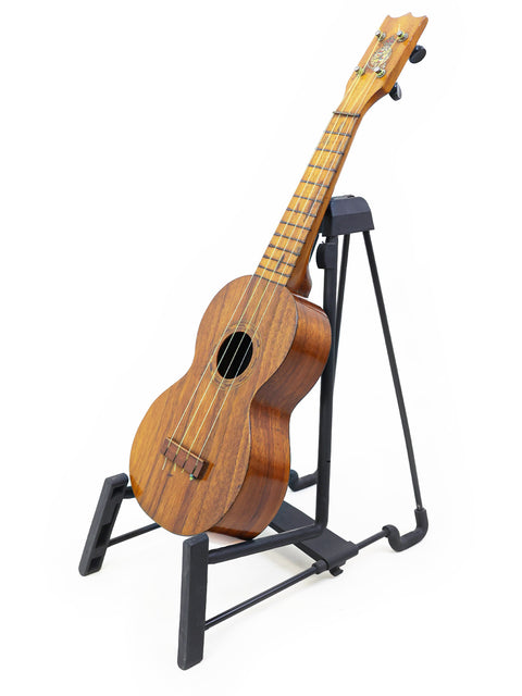 A historic Kaai Style 2 Koa Ukulele from Hawaii (c. 1918) elegantly positioned on a black stand.