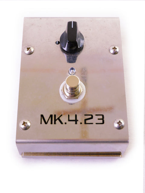 A metal plate with a black switch, central silver button, and "MK.4.23" label.