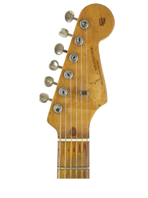 A pristine white background features the neck of a vintage 1958 Fender Stratocaster, showcasing its iconic design.