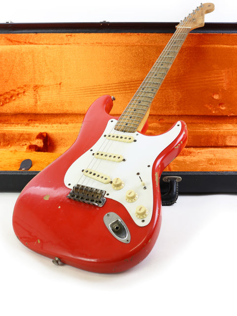 A red 1958 Fender Stratocaster electric guitar displayed in a vivid orange case, capturing its timeless vintage appeal.

