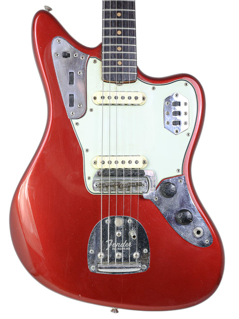 A red 1964 L-Series Fender Jaguar guitar featuring a white pickguard, highlighting its vintage charm and refinished condition.
