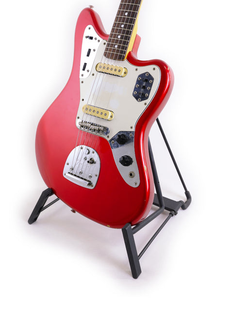 A red Fender CIJ Jaguar electric guitar from Japan, 1999-2002, displayed elegantly on a stand.