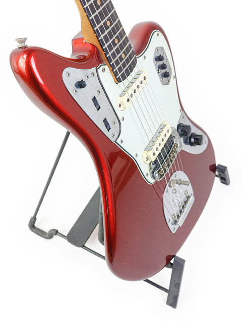 A red electric guitar on a stand, highlighting the vintage 1964 USA Fender Jaguar Refinish craftsmanship.