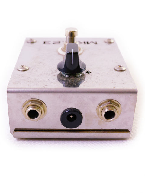 A silver guitar pedal with knob and input/output jacks on white background.