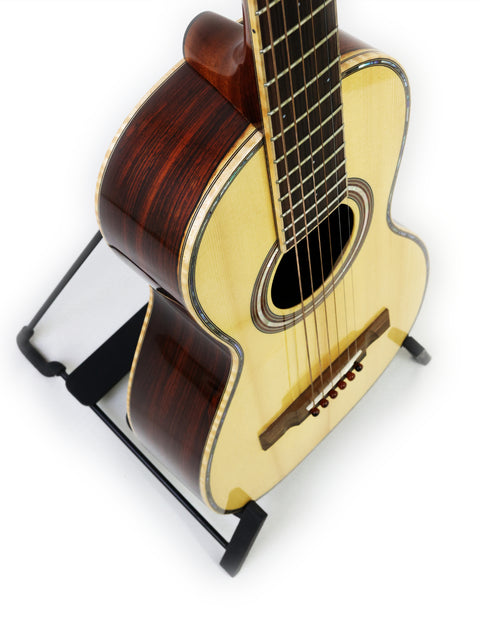 A small guitar resting on a stand, set against a white backdrop, emphasizing its shape. Gilet Bay State, Australia 2018.

