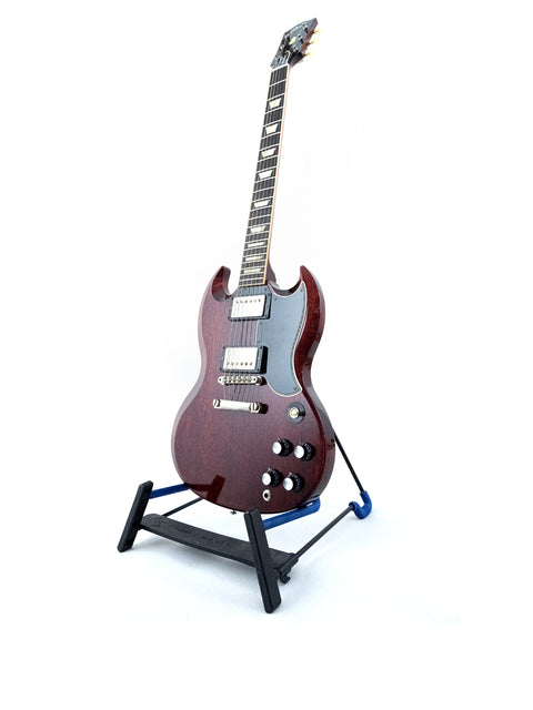 A striking Gibson Custom ’61 Les Paul SG Standard guitar resting on a stand with a black base, emphasizing its classic appeal.
