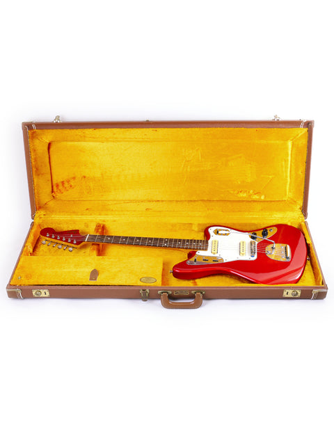 A striking red Fender CIJ Jaguar guitar nestled in a case, displayed on a pristine white background, highlighting its elegance.