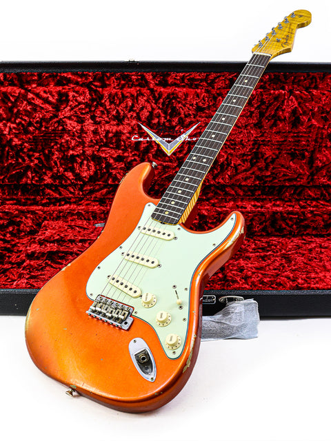 A striking red case housing a Fender Ltd NAMM '64 Stratocaster Relic guitar, showcasing its timeless design and artistry.