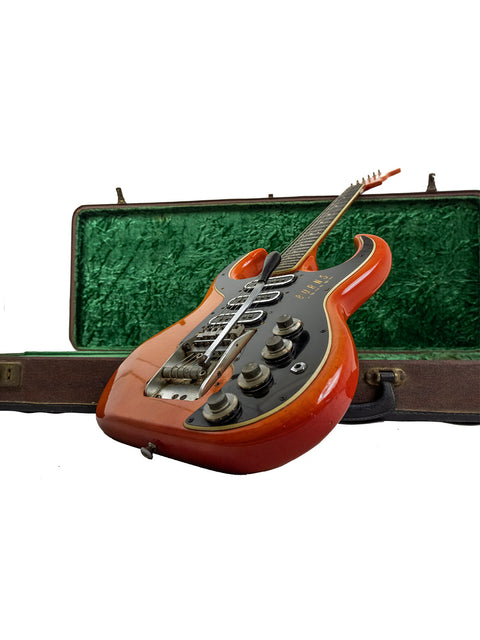 A striking red guitar, a Warmoth Strat Partscaster from 2012, safely stored in a green case, ready for its next performance.
