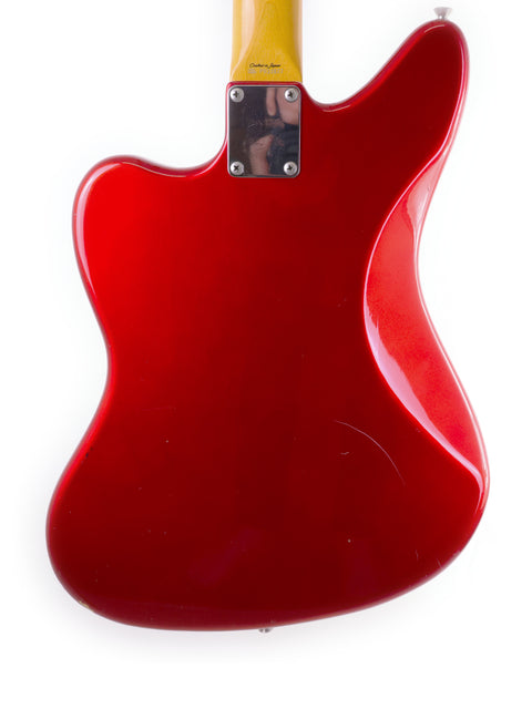 A striking red guitar featuring a yellow neck, identified as a Fender CIJ Jaguar made in Japan from 1999 to 2002.