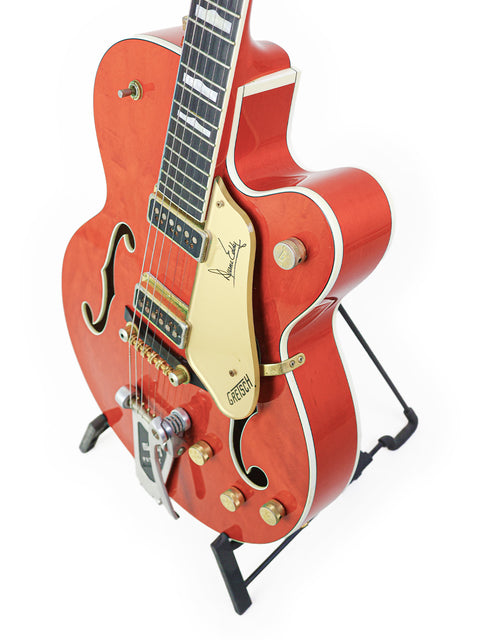 A striking red guitar, the Gretsch 6120DE Duane Eddy Signature from 1997, featuring a shiny gold pick guard.