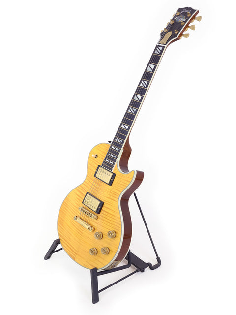A striking yellow Gibson Les Paul Supreme electric guitar from 2003, resting on a stand, highlighting its unique style.