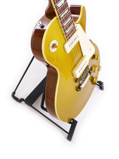 A striking yellow electric guitar rests on a stand, identified as the Gibson Custom Historic VOS LPR-6 1956 Reissue Gold Top.