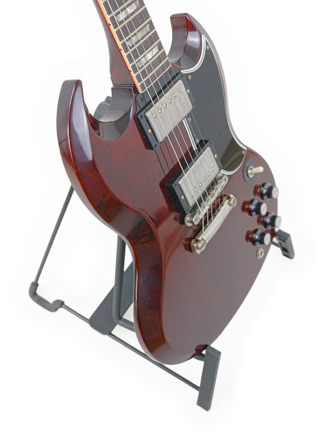 A stunning Gibson Custom Shop '64 SG Standard guitar displayed on a black base stand, highlighting its craftsmanship.