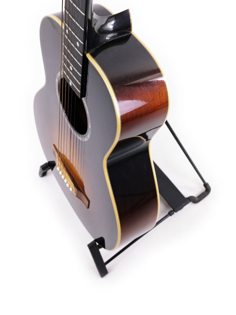 A stunning black guitar on a stand, the Beau Hannam Parlour from Australia, 2009, highlighting its sleek design.